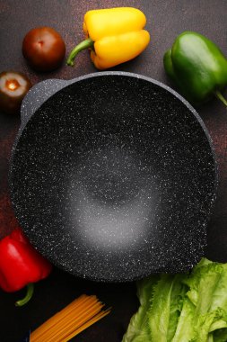 İçi malzemelerle dolu boş tava. Metal mutfak arka planında taze sebze ve baharatlar