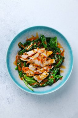 Beyaz somut arkaplan üzerinde ıspanak üst görünümü ile ızgara kalamar.