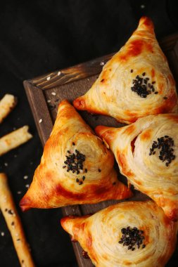 Samosa, samsa etli turta, doğu usulü. Özbek ulusal yemeği samosa ahşap ve siyah arkaplan