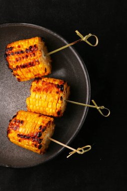 Koyu arkaplanda ızgara mısır. tereyağlı ve tuzlu mısır.