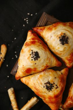 Samosa, samsa etli turta, doğu usulü. Özbek ulusal yemeği samosa ahşap ve siyah arkaplan