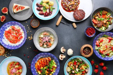 Masa yemeği manzaralı. Tabakları masaya koyun. Uluslararası karışık yiyecekler. Vejetaryen, et ve çiğ et.