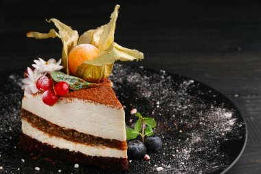 Böğürtlenli kek. Böğürtlenli kremalı pasta, bitki salatası ve siyah tabakta diğer meyveler..