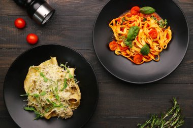 Makarna manzaralı iki tabak. sığır etli alfredo makarna ve ahşap masa üzerinde marinara makarna malzeme, biber ve peynir ile.