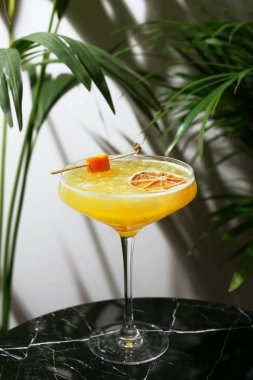 Mermer masaya yakın narenciye kokteyli ve arka planda tropik bitkiler. Meandrin veya mandalina kokteyli. Yaz taze içecekleri.