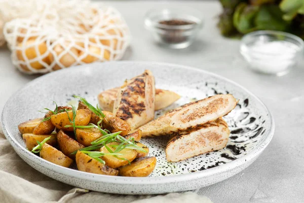 Idaho patatesli ızgara tavuk bifteği. Seramik tabakta, beton masada malzemelerle..