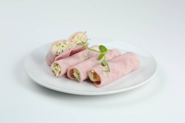 Beyaz tabakta peynirli jambon rulosu. Mortadella ve ricotta börekleri beyaz arka planda izole edilmiş..