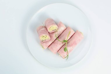Beyaz tabakta peynirli jambon rulosu. Mortadella ve ricotta börekleri beyaz arka planda izole edilmiş..