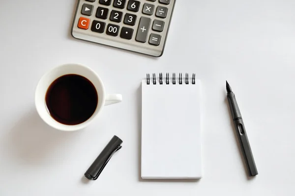 Kaffekopp, spiral notebook, kalkylator och penna på vit bakgrunds — Stockfoto