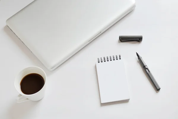 Taza de café, cuaderno en espiral, computadora portátil y pluma sobre fondo blanco — Foto de Stock