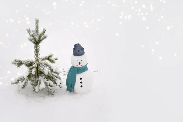 Sneeuwman draagt een wintermuts. sjaal op witte achtergrond en staande bij een boom. — Stockfoto