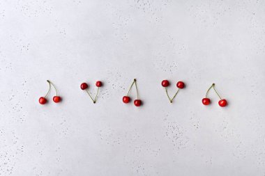 Gri arka planda olgun kırmızı kirazlar. Metin, düz yatak ve üst görünüm için boşluk kopyala.