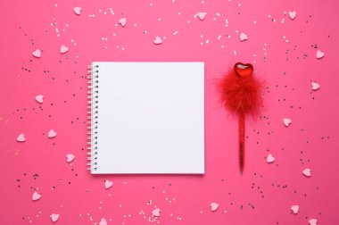 Kalemin yanında kalpler olan pembe arka planda beyaz boş bir defter. Uzayı kopyala Metninize göre yerleştirin. Sevgililer Günü, aşk konsepti. Üst görünüm.