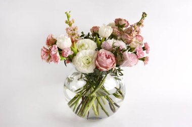 Vazodaki güzel çiçekler beyaz arkaplanlı bir masanın üzerinde. Kadınlar, anneler günü, aşk konsepti. Bahar, yaz mevsimi. Ön görünüm.