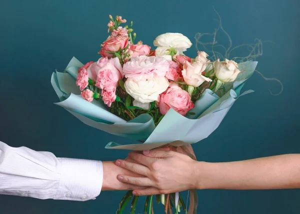 Man holding and giving a beautiful bouquet with flowers to woman on green background. Front view. Valentines, womens, mothers day, love concept.