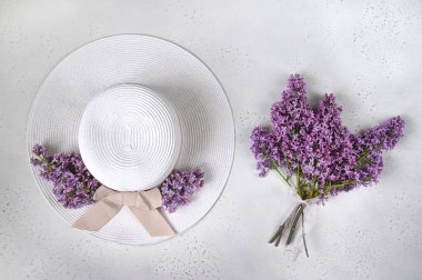 Masada leylak çiçekleri ve şapka. Bahar, gelişim konsepti. Düz yatıyordu. Üst görünüm.