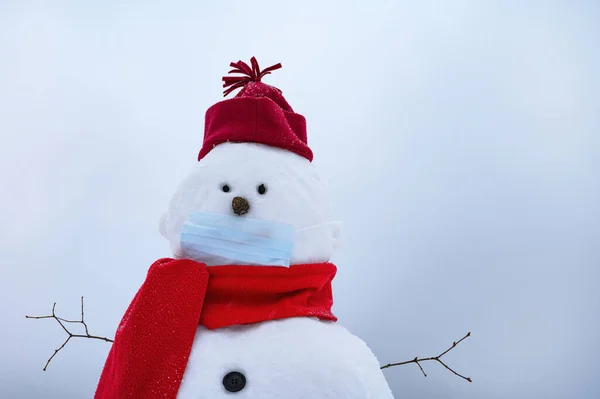 Sneeuwman met gezichtsmasker, winterhoed. sjaal op een witte achtergrond — Stockfoto