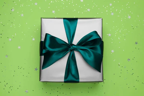 Подарочная коробка с луком на зеленом фоне с блестками. — стоковое фото