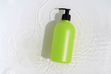 Beyaz arka planda su ve çiçekli kozmetik şişesi. Üst görünüm, yakın plan.