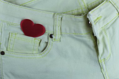 Açık kotun cebinde küçük ipek kırmızı kalp. Yukarıdan görüntüle.