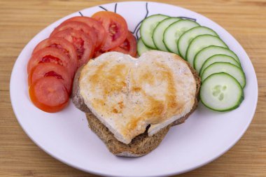 Kalp şeklinde sebzeler ve ahşap arka planda biftek. Sevdiğin için kahvaltı..