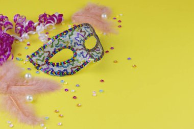 Karnaval. Şenlik arka planı. Venedikli. Sarı arka planda tüyleri ve süslemeleri olan karnaval maskesi. Brezilyalı. Boşluğu kopyala.