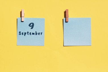 9 Eylül. Ayın dokuzuncu günü, takvim tarihi. Sarı arka plana yazmak için iki mavi çarşaf. Üst görünüm, boşluğu kopyala. Sonbahar ayı, yılın günü konsepti..
