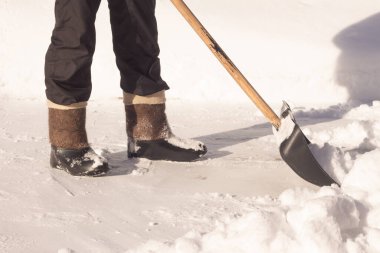 Bir adam yoğun kar yağışı sonrasında evinin önündeki kaldırımdan kar temizler..
