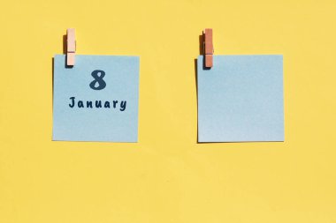 8 Ocak. Ayın sekizinci günü, takvim tarihi. Sarı arka plana yazmak için iki mavi çarşaf. Üst görünüm, boşluğu kopyala. Kış ayı, yılın günü konsepti.