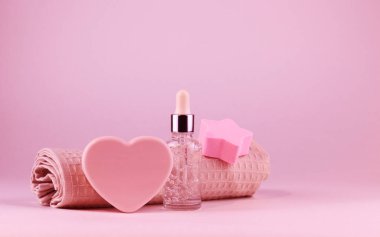 Face serum bottle, natural heart-shaped soap and rose towel. The concept of natural organic products and caring for your skin.