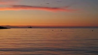 Ufukta bir gemiyle denizde turuncu gün batımı. Sessiz, huzurlu bir akşam manzarası. Seyahat ve eğlence kavramı. Tam sakin ve küçük dalgalar. Sivastopol, Kırım 'daki sahil.