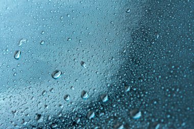 Yağmur damlaları ve güzel mavi bokeh ile soyut bir arkaplan. Sonbahar ve soğuk fırtınalı hava kavramı. Pencerenin bulanık arka planında makro damlaların dokusu. Yalnızlık, üzüntü.