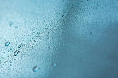 Yağmur damlaları ve güzel mavi bokeh ile soyut bir arkaplan. Sonbahar ve soğuk fırtınalı hava kavramı. Pencerenin bulanık arka planında makro damlaların dokusu. Yalnızlık, üzüntü.