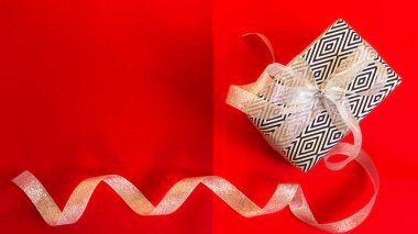 Kırmızı arka planda yeni yıl hediyesi. Mutlu Noeller ve mutlu yıllar. Renkli parlak tasarım. Siyah beyaz hediye paketi. Noel arkaplan görüntüsü, düz plan, pankart, kartpostal, kopyalama alanı