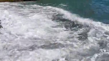 Turkuaz dalgalar kumsalda yuvarlanıyor. Dalgaların hızlı hareketi. Temiz ve berrak deniz suyu. Kumsalda küçük çakıl taşlarıyla güneşli bir yaz günü. Sıcak ve köpüklü deniz sörfü.