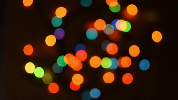 カラフルなボケのライトが暗闇の中で点滅します クリスマス休暇の抽象的な背景 魔法に近づくという概念 クリスマスツリーガーランドでのフィールドの浅い深さ — ストック動画