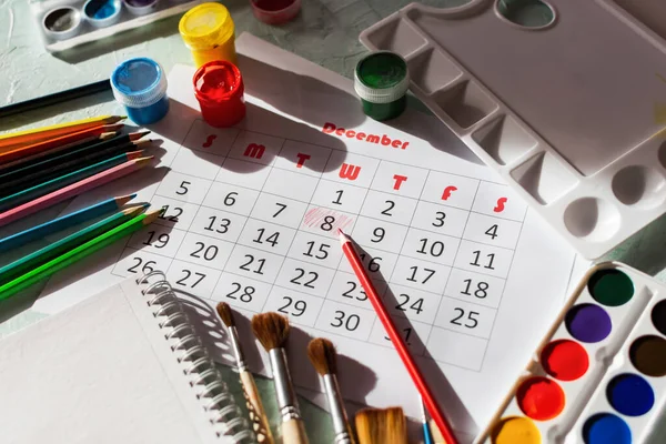 Calendar for December 2021. The creative layout of the objects for drawing. December 8 is the Artist\'s Day. Greeting card layout Watercolor, gouache paints, colored pencils, brushes, palette, flat lay