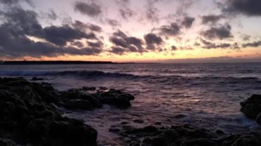 Büyük dalgalar kayalara çarpıyor. Gün batımında denizde fırtına. Ufkun alt çizgisi, dalgaların yakın çekimi. Yavaş çekim uçan sprey. Sıcak günbatımı ışığında doğal deniz arka planı.