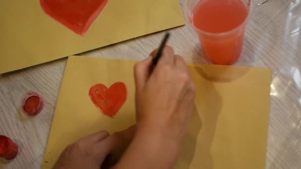少女は赤いアクリル絵具で紙に心を描きます 愛のシンボル バレンタインデー クリエイティブパッケージ バレンタインデーカード お祝いの気分の概念 2月14日の贈り物 — ストック動画