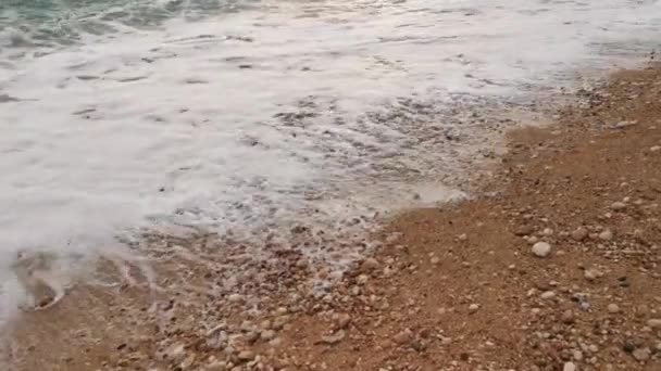 绿松石的波浪在海滩上翻滚 波浪的快速运动 清澈的海水 夏日阳光明媚 沙滩上布满了小鹅卵石 温暖而起泡的海浪 — 图库视频影像