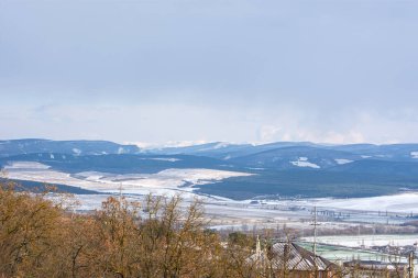 Kırım dağlarında kış. Sugar Head köyü manzarası ve kar örtüsü içinde bir dizi dağ. Sivastopol, 18 Ocak 2021. Özel konut, çam ormanı, yol manzaralı..