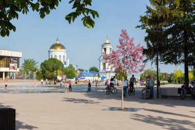 8 Mayıs 2019 'da Voronezh' deki Pokrovsky Katedrali. Pokrovskaya Meydanı 'ndaki çeşmede gökkuşağı ve insanlar var. Orta Rusya 'ya git. Kaygısız insanlar şehir meydanında dinleniyor. .