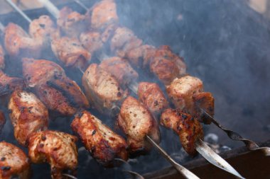 Şiş kebap şiş ızgara. Domuz rostosunun lezzetli arka planı, sığır eti. Yaz tatili konsepti, piknik. Açık ateşte et pişirmek. Lezzetli çıtır ızgara ızgara. Atmosferik duman