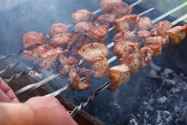 Şiş kebap şiş ızgara. Domuz rostosunun lezzetli arka planı, sığır eti. Yaz tatili konsepti, piknik. Açık ateşte et pişirmek. Lezzetli çıtır ızgara ızgara. Atmosferik duman