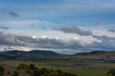 Tarlanın üzerinde fırtına bulutları var. Gri, uzun, büyük bulutlar gökyüzünde asılı. Yakında yağmur yağacak. Kırsal yaz manzarası. Kötüleşen hava konsepti, yağmurun yaklaşması. Dramatik bulutlu görünüm