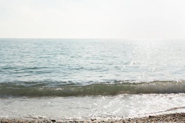 Gümüş deniz ışıl ışıl arka plan. Grinin ve gümüşün gölgeleriyle minimalist yaz manzarası. Gün ortası sıcak. Parlak güneş dalgalara yansıyor. Kopya alanı ile doğal yatay arkaplan