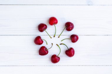Kiraz beyazı ahşap arka plan. Masanın üstünde olgun, sulu kiraz meyveleri. Tazelik, düzgün beslenme, vitaminler. Yaratıcı düz plan. Merkezi minimalist kompozisyon.