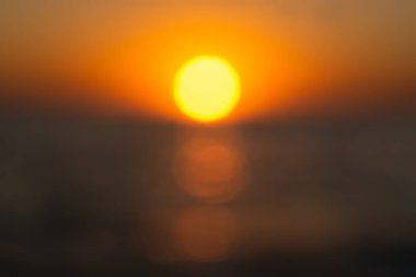 Yaz güneşi bulanık bir günbatımı arka planıdır. Yaz tasarımı için ateşli bir arka plan. Güzel Bokeh, parlak deniz, gün batımının ılık ışınları ya da şafak. Yuvarlak sarı güneşin soyut arkaplan görüntüsü