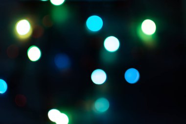 Siyah arka planda çok renkli bir bokeh. Tatil ışıklarının parlak bulanık dokuları. Bulanık arka planda renkli güzel Noel çelenkleri. Yeni yıl için bir tebrik kartının taslağı. Boşluğu kopyala