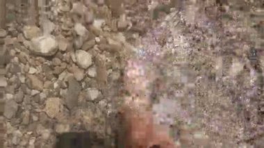 Temiz bir nehir. Genç bir kadın soğuk bir dağ nehrinden geçiyor. Kayalık dibi olan en saf su yukarıdan görülür. Güzel güneş parlıyor. Yürüyüş konsepti, ekstrem sporlar, yaz seyahati